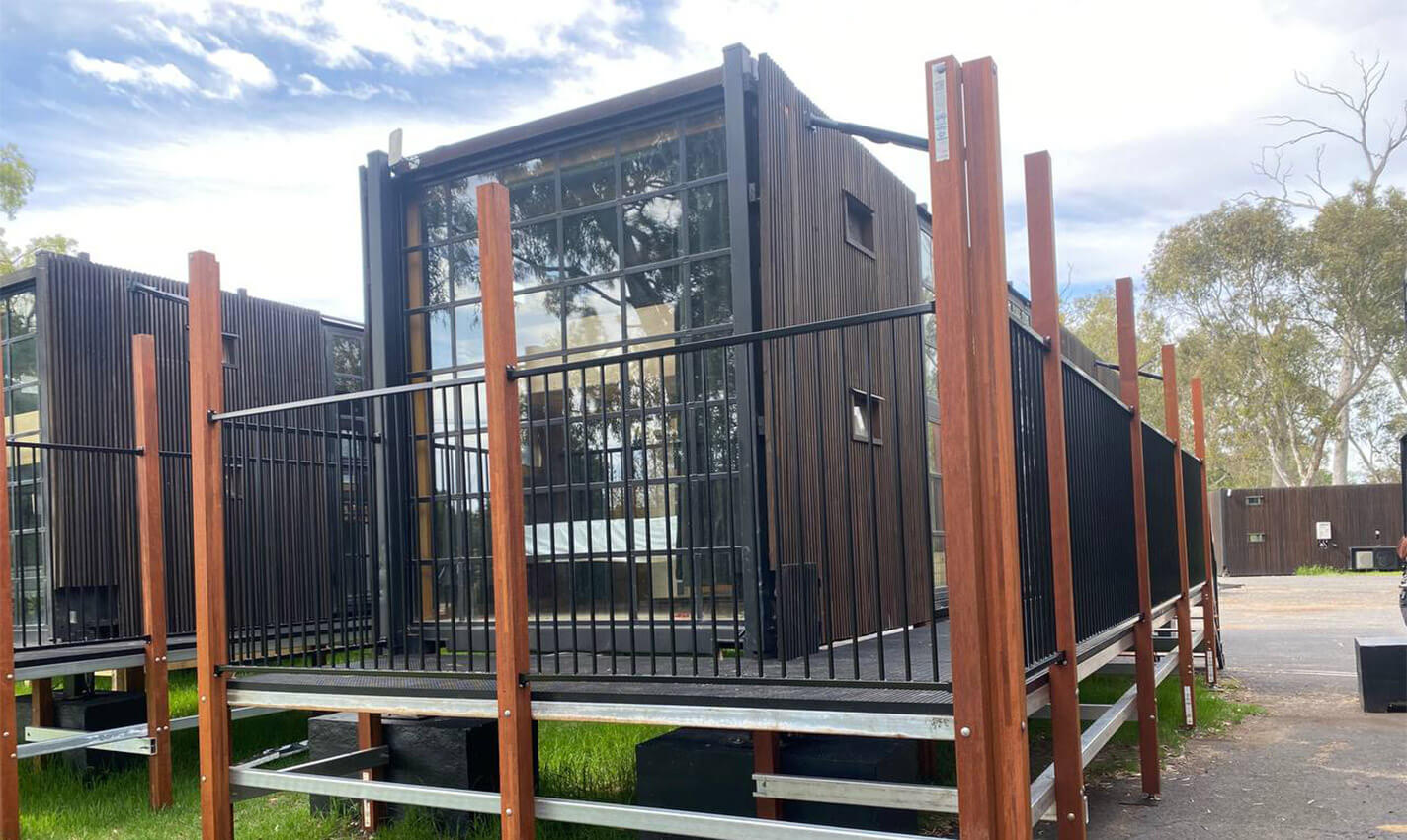 Charming cabin featuring a wooden deck and seating area, nestled among trees, creating a welcoming retreat at Stawell Hotel Motel Accommodation, perfect for relaxation and enjoying nature