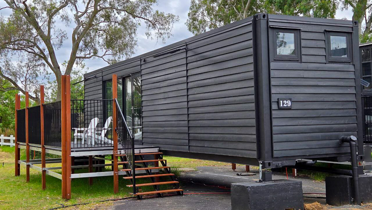 Charming cabin featuring a wooden deck and seating area, nestled among trees, creating a welcoming retreat at Stawell Hotel Motel Accommodation, perfect for relaxation and enjoying nature