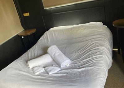 Double bed with fresh towels and two side tables in Cabin 54. One of the Cabins, Dwellings, Caravans, & Glamping Tents at Stawell Grampians Gate C&C Park.