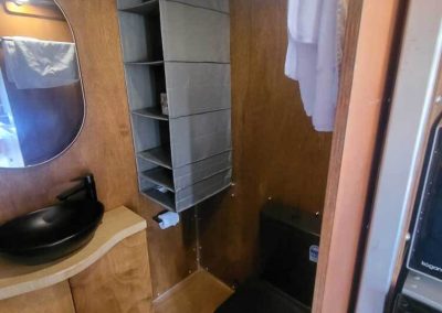 Compact bathroom with black basin and toilet inside a timber-finished caravan. One of the Cabins, Dwellings, Caravans, & Glamping Tents at Stawell Grampians Gate C&C Park.