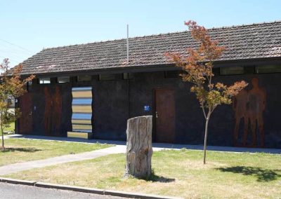 Exterior of amenities block featuring modern murals and corrugated metal accent. One of the Cabins, Dwellings, Caravans, & Glamping Tents at Stawell Grampians Gate C&C Park.
