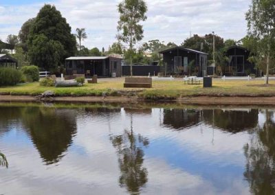 Cabins and communal spaces at Stawell Grampians Gate C&C Park overlooking a peaceful lake with clear reflections. One of the Cabins, Dwellings, Caravans, & Glamping Tents at Stawell Grampians Gate C&C Park.