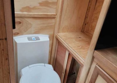 Compact bathroom inside one of the retro vans, featuring a modern toilet and timber cabinetry – one of the Cabins, Dwellings, Caravans, & Glamping Tents at Stawell Grampians Gate C&C Park.