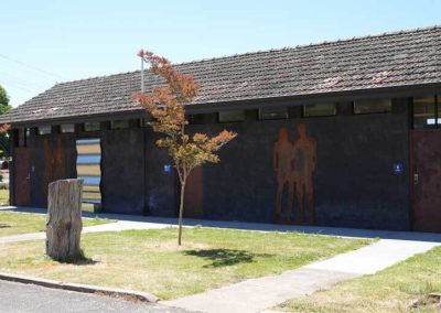 Public amenities building with male and female signage, dark exterior walls, and artistic silhouettes at Stawell Grampians Gate C&C Park.