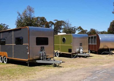 A colourful lineup of modern retro vans, offering stylish, compact accommodation at Stawell Grampians Gate C&C Park.
