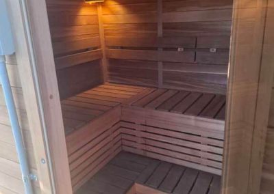 Warmly lit wooden sauna interior with tiered bench seating at off-grid wellness retreat in Stawell Grampians Gate C&C Park.