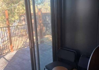 Compact workspace pod with sliding doors and seating, overlooking tranquil nature views in Stawell Grampians Gate C&C Park.