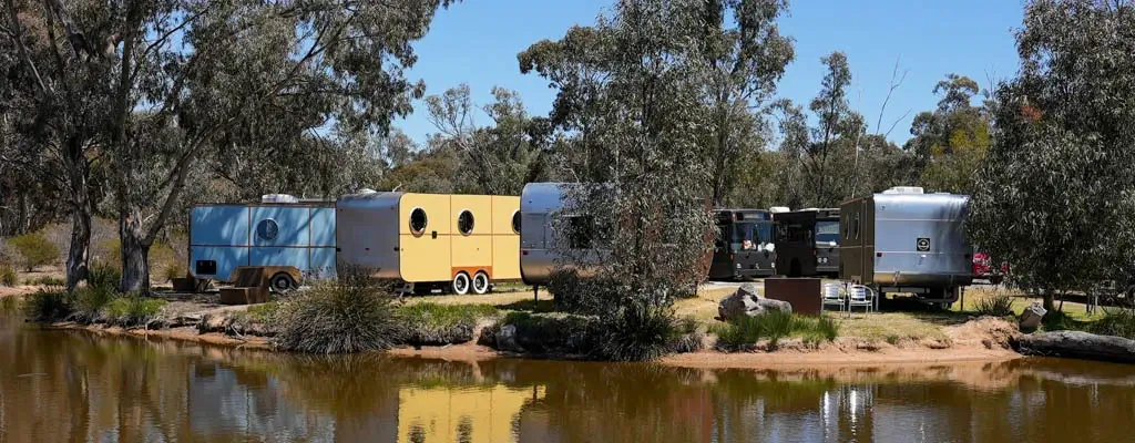 A colourful lineup of modern retro vans, offering stylish, compact accommodation at Stawell Grampians Gate C&C Park.