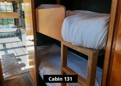 Wooden bunk beds inside Cabin 131 at Stawell C&C Park, showing a private sleeping area with thick mattresses, white bedding, and a timber ladder – ideal for families or group stays.