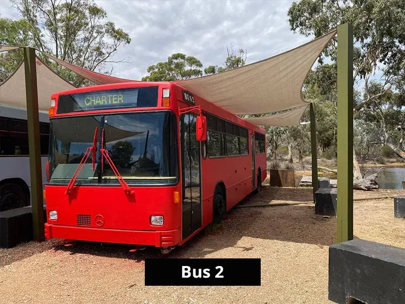 Black vintage bus converted into holiday accommodation parked beside a lake at Stawell Caravan Park.