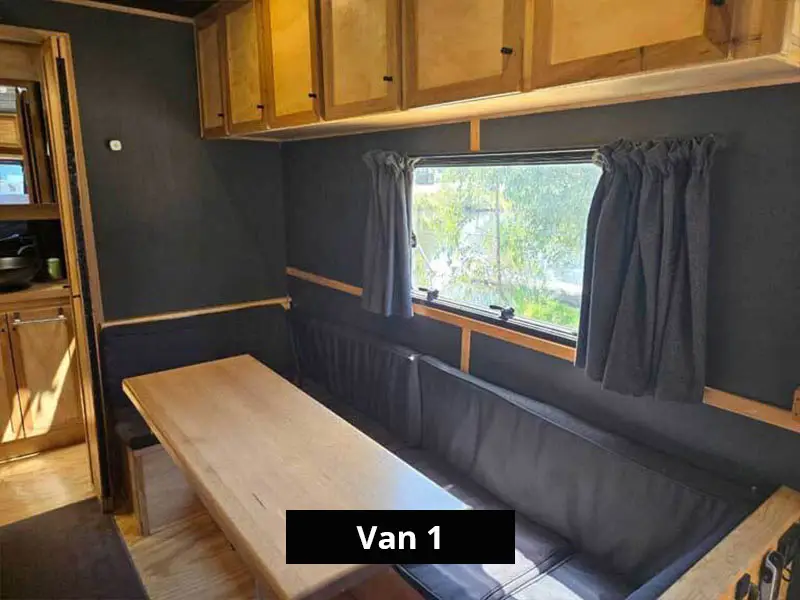 Van dining area with bench seating, timber table, large window and overhead storage