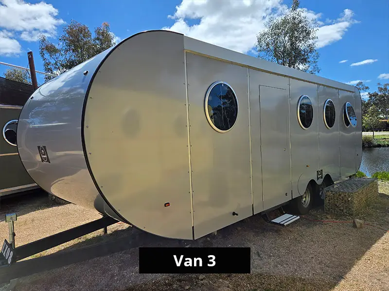 Modern caravan exterior with curved aluminium front, white paneling and round windows